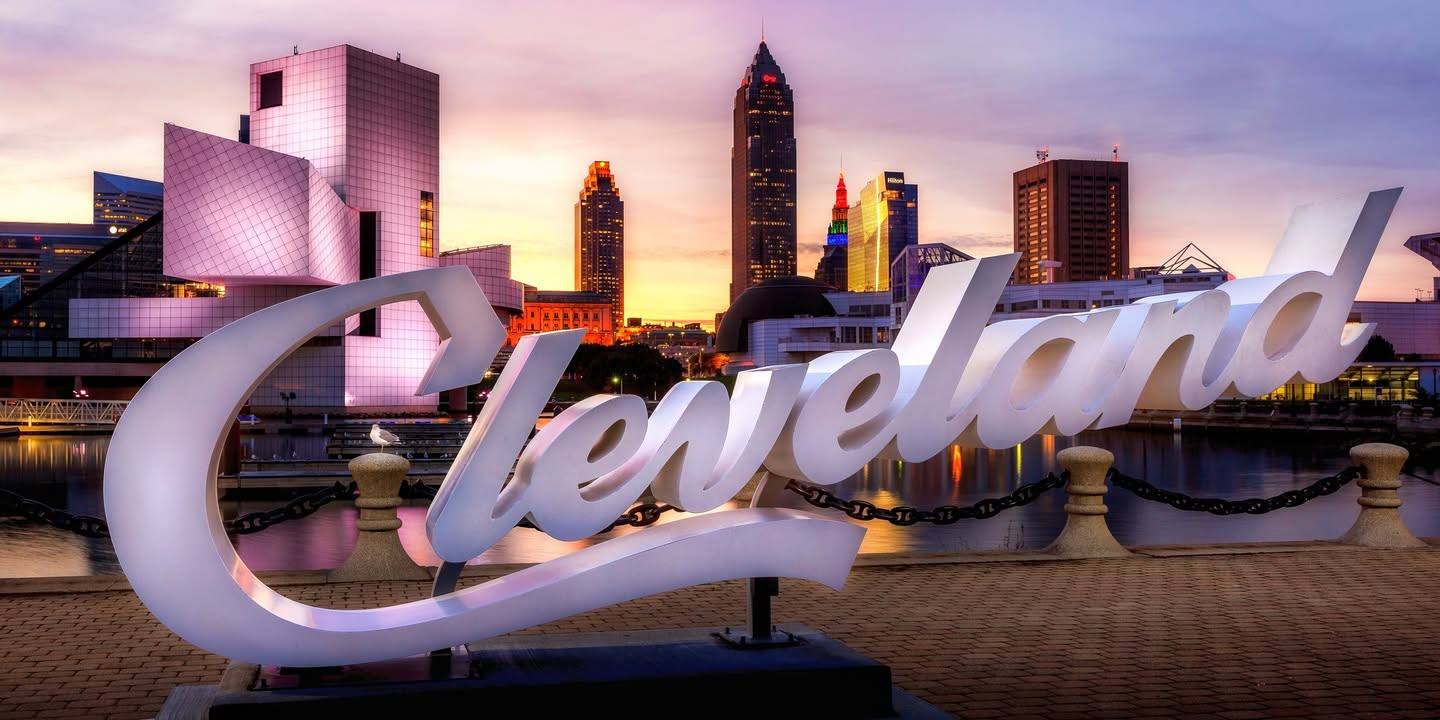 Панорама центра Кливленда в сумерках за надписью Cleveland